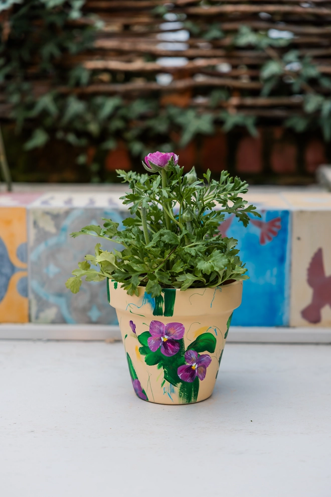 hand painted terrecotta floral plant pot background in a pale yellow with pink and white blossom flowers