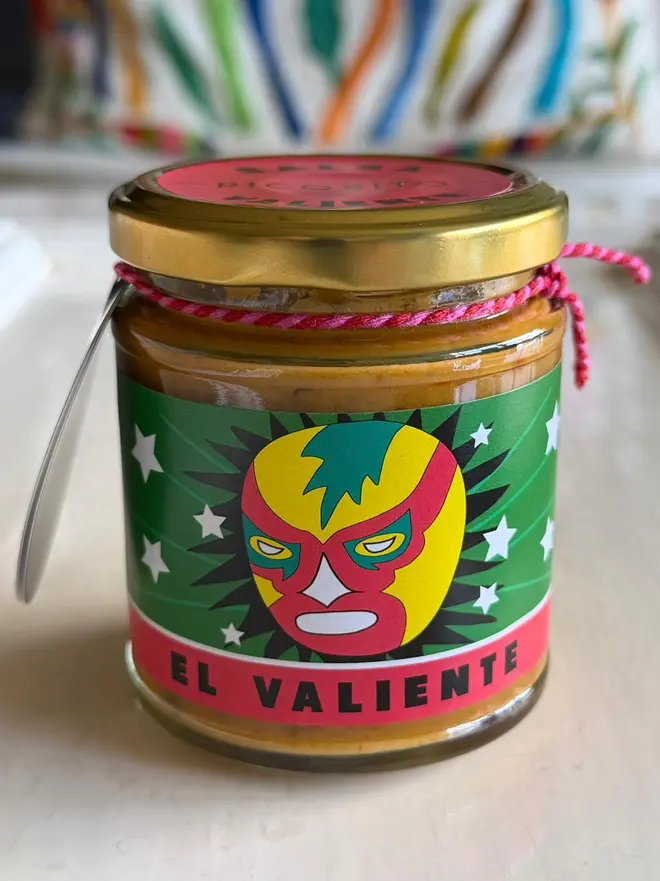 'El Valiente' Salsa Jar (Set Of 1-4 Jars), a salsa jar sitting on a kitchen counter top. It has the icon of a masked figure. 