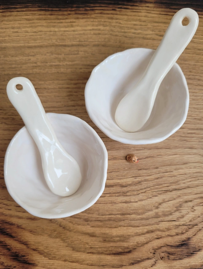 a shot from above of a pair of white ceramic pinch pots with a ceramic white spoon in both