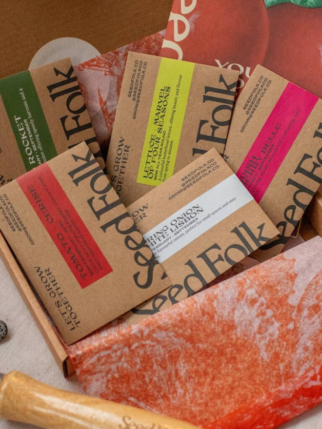 the salad bowl seed collection. box in pink and red packaging with illustrated tomatoes photographed open to show seed packets inside