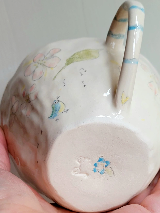 close up phot of a hand made ceramic cup with a blue handpainted forget me not flower on the base