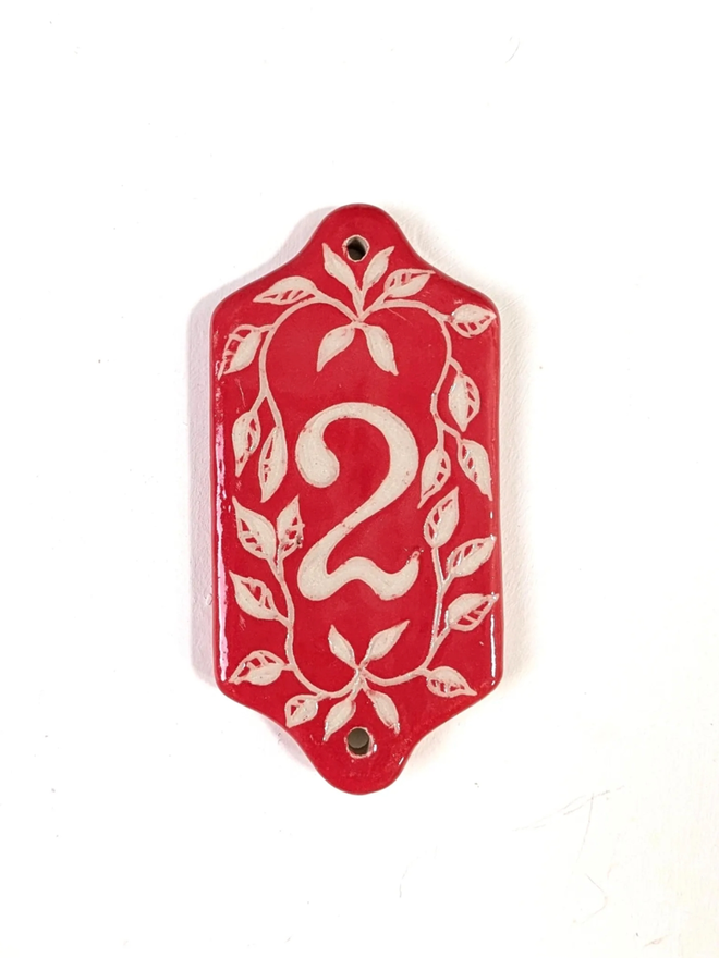 Red Sgraffito Leaf Address Tile. A tile with ‘2’.