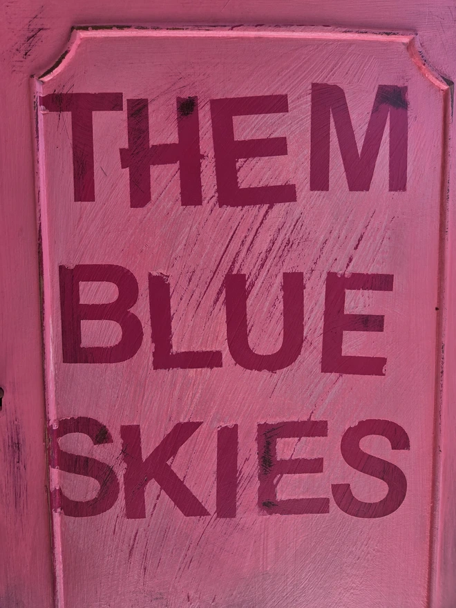 Close up of lettering on painted vintage wooden cabinet with pink, blue and floral decoration