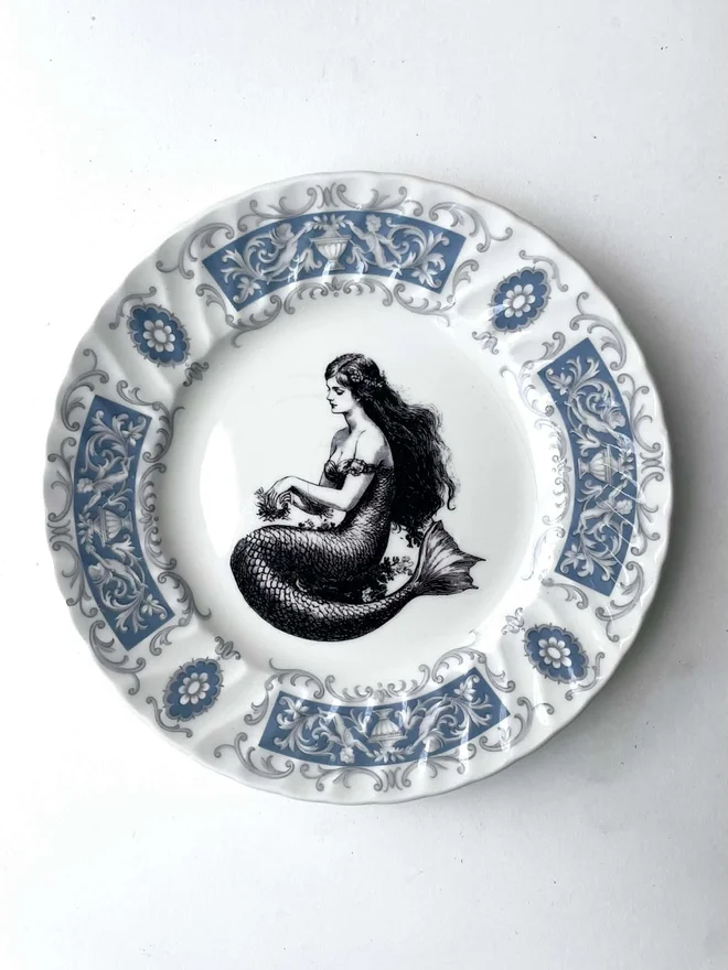 vintage plate with an ornate border, with a printed vintage illustration of mermaid in the middle