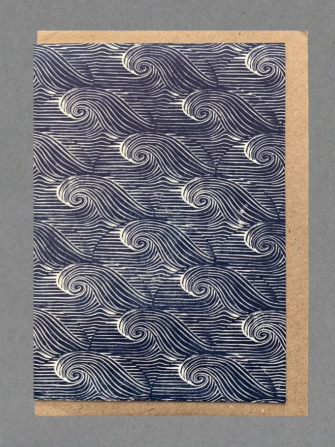 Card with blue and white waves on it with a brown envelope behind