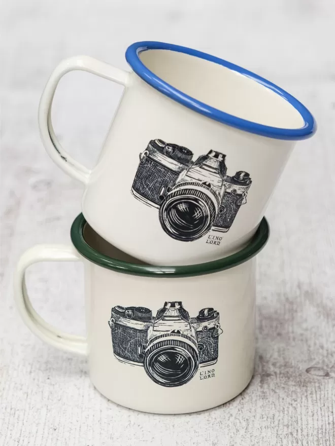 Picture of 2 Cream Enamel Mugs with a Camera design etched onto it, taken from an original Lino Print
