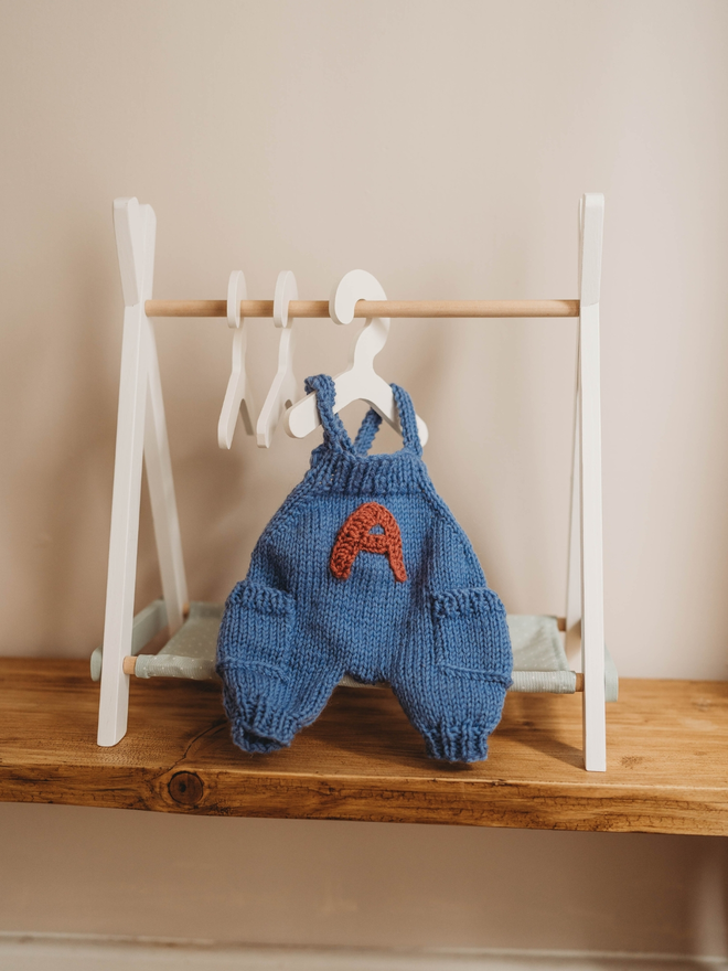 hand knitted personalised blue teddy bear dungarees on toy clothes rail