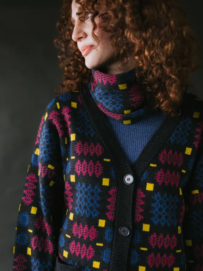 Model wearing pieces from MABLI's 'Carthen' collection, featuring the Carthen Wrap in the vibrant 'Fireworks' colour-way. The design showcases bold, colourful patterns inspired by traditional Welsh blanket tapestry.