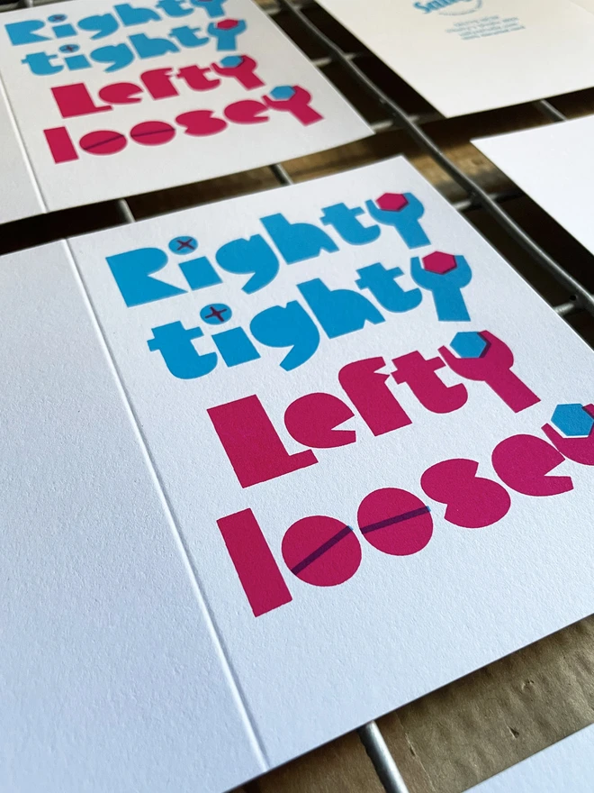An angled shot of several unfolded screen printed Righty tighty, lefty loosey cards on a drying rack