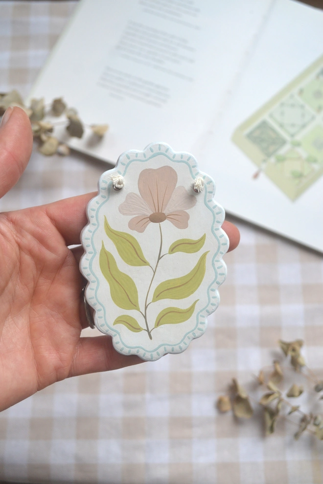 hanging ceramic ornament with blue border and pink an green flower