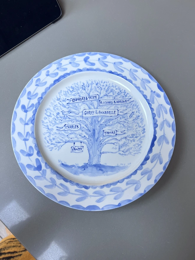 Blue and white hand-painted family tree plate including sign for the pet