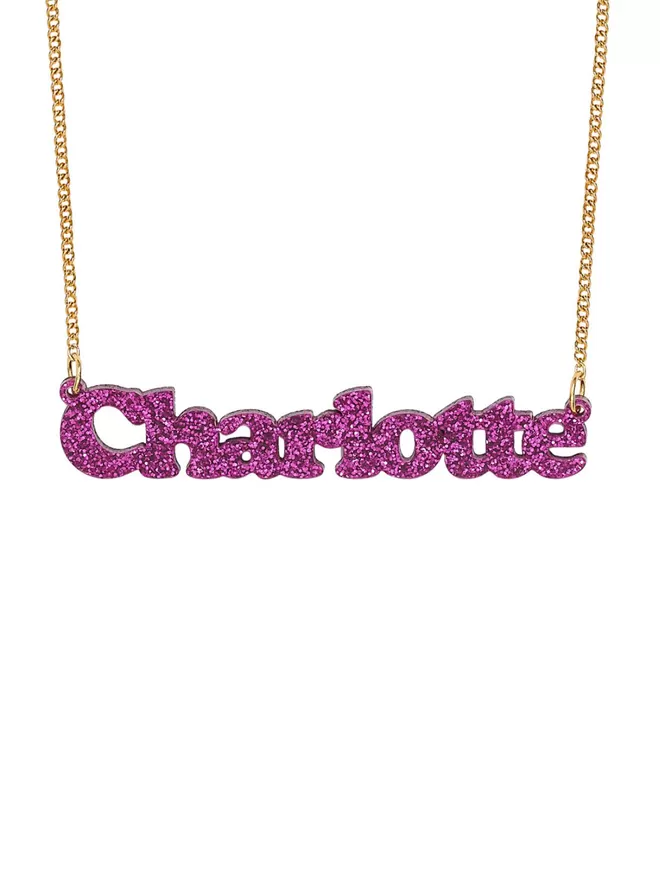 Personalised Name Neckace from Tatty Devine. The Necklace is the word Charlotte laser cut from Deluxe Magenta Glitter Acrylic on a gold-plated chain.