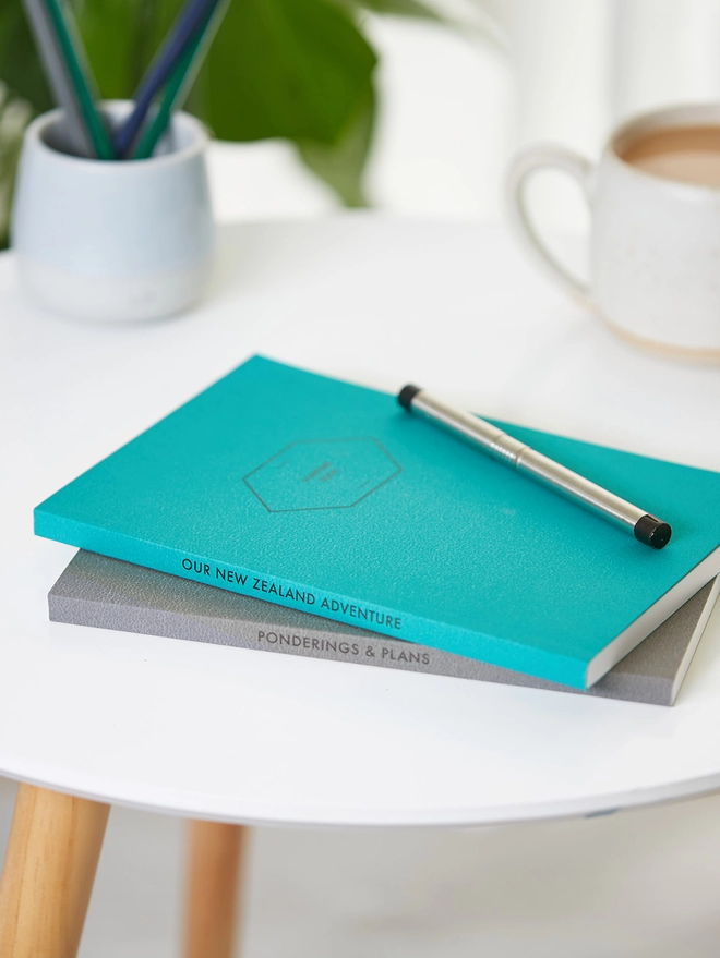 two colourful notebooks with personalised text down the spine
