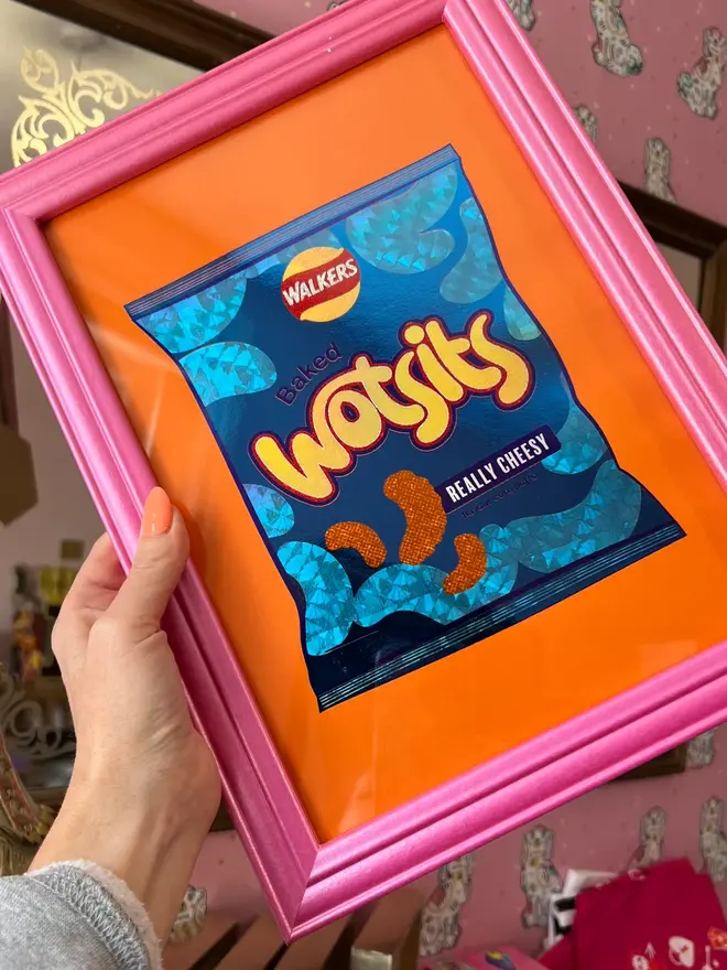 'Wotsits' ScreenPrint, a person holding a colourful wotsits screenprint in a frame. 
