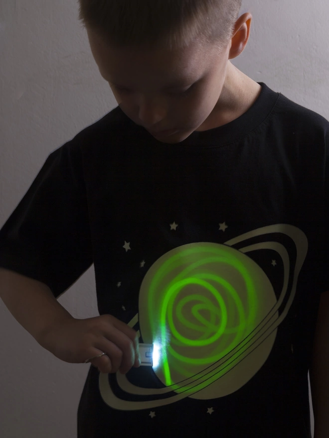 Boy drawing onto solar printed tshirt with light