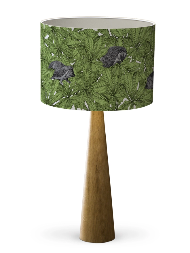Drum Lampshade featuring hedgehogs in green leaves with a white inner on a wooden base on a white background