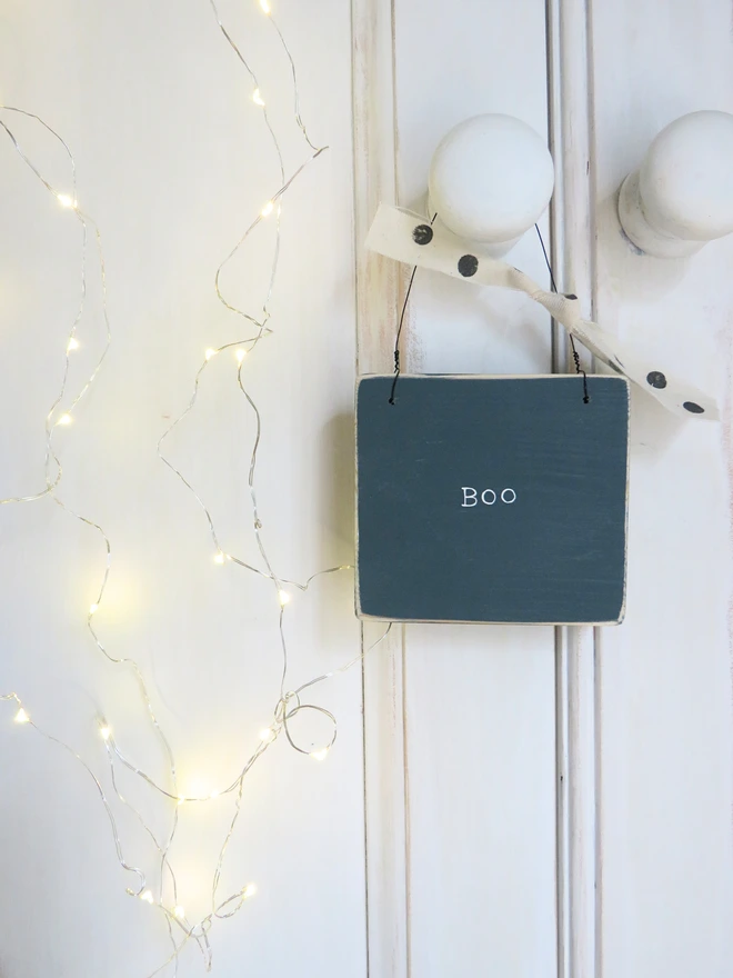 inky blue hand painted wooden sign with boo message and spotty ribbon detail