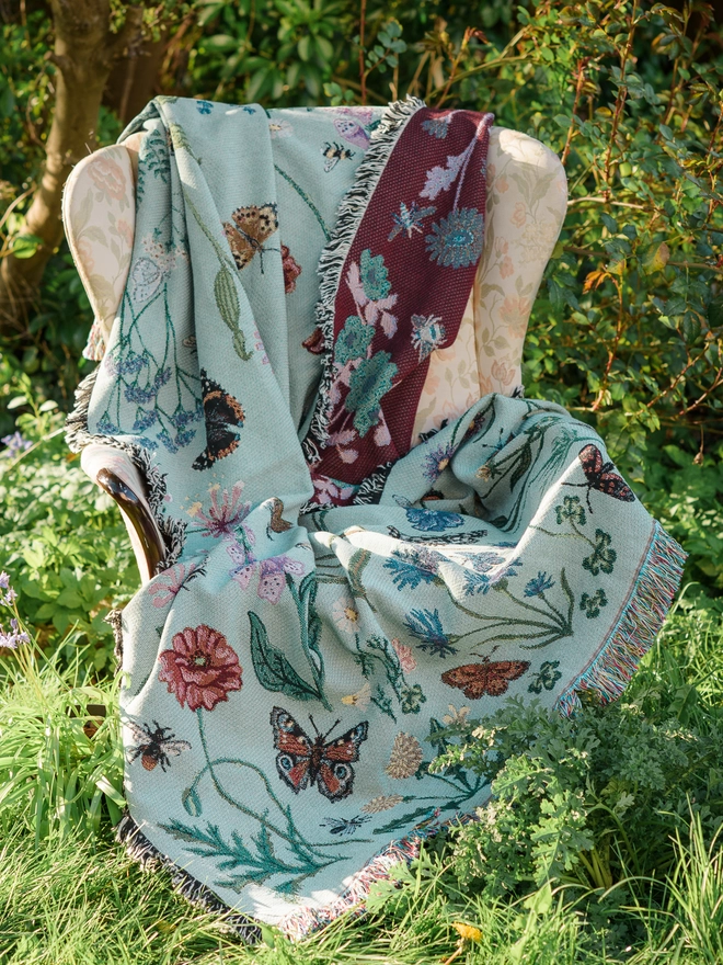 'Pollination Meadow' Recycled Cotton Blanket seen on a chair outside.