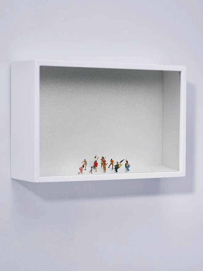 Miniature scene in an artbox showing about 15 tiny people dancing their hearts out, set against a sparkling white backdrop (whole artwork). 