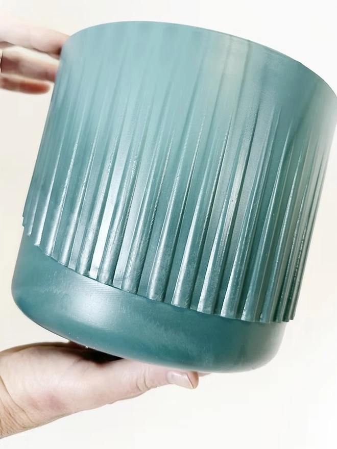 Ocean Plastic Plant Pot Medium, a recycled blue plant pot sitting on a plain surface against a white backdrop. 