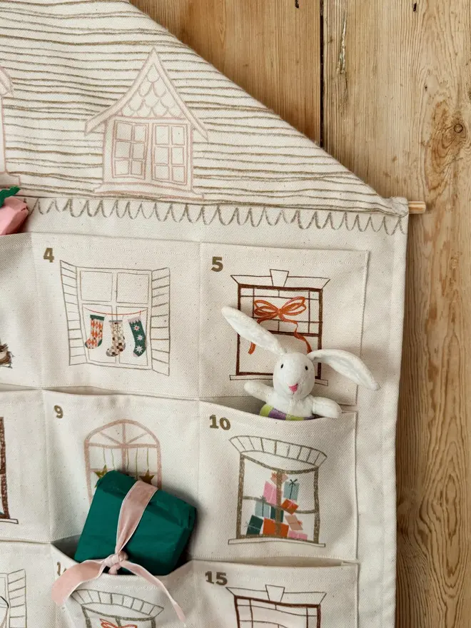 Fabric Christmas House Advent Calendar, with a little girl putting in a present. 