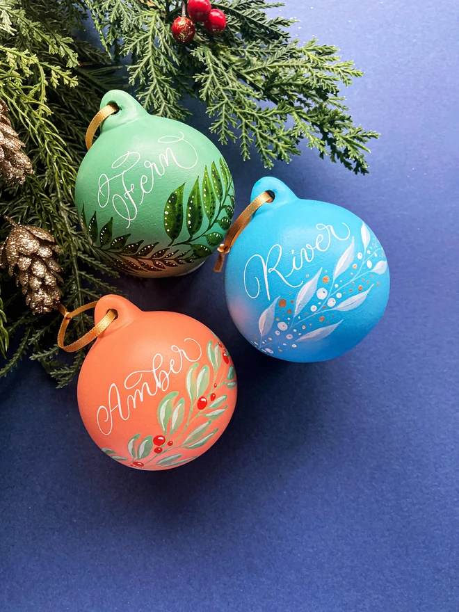 Three Christmas baubles personalised with calligraphy