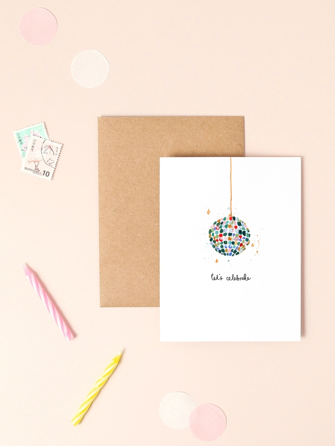 A vibrant illustration featuring a sparkling disco ball adorned with colorful glitter accents, exuding a festive and celebratory atmosphere. The design is complemented by the playful message "Let's celebrate" in a whimsical, handwritten font. The combination of shimmering details and bold colors captures the excitement of a party, making this mini card a perfect choice for birthdays, anniversaries, or any occasion that calls for a touch of sparkle and joy.