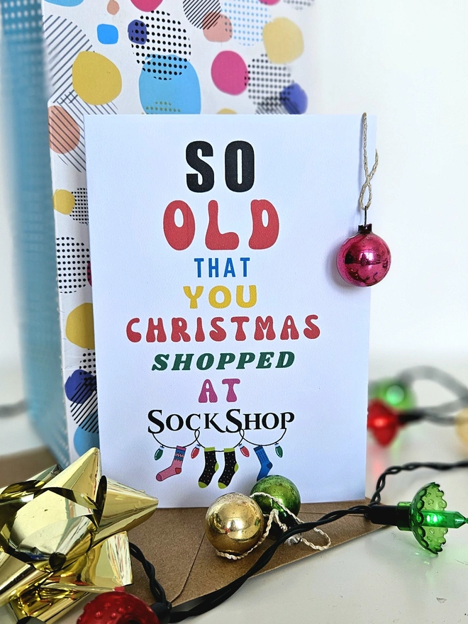 A photograph of the front of a humorous A6 greeting card illustrated using brightly coloured text and the retro shop logo. The text says so old you Christmas shopped at Sock Shop