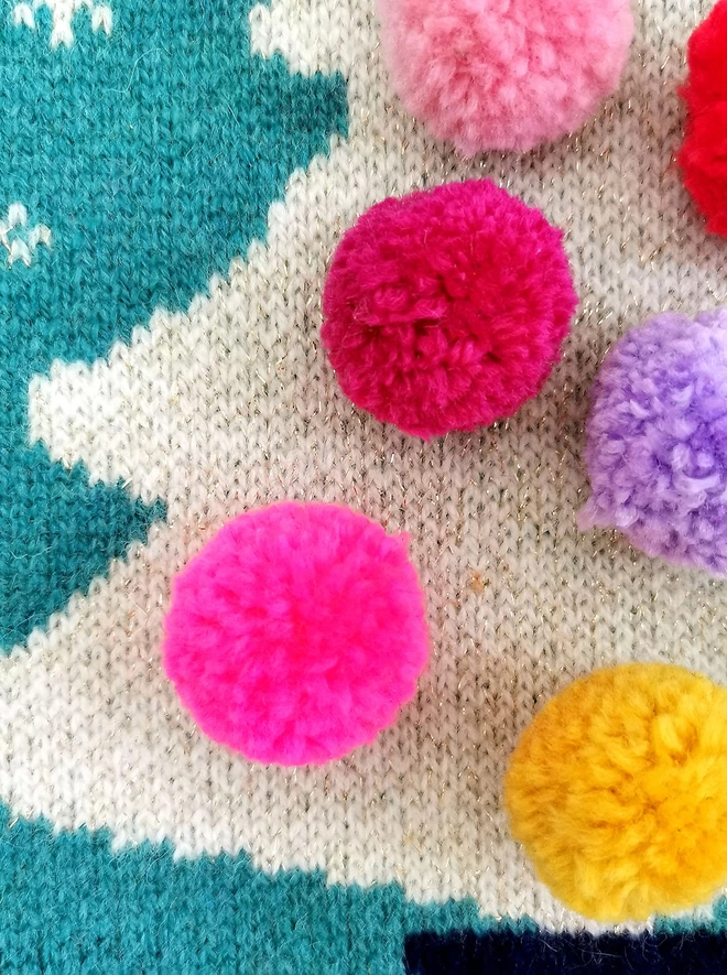 A close up of the pom poms on the Christmas tree base.
