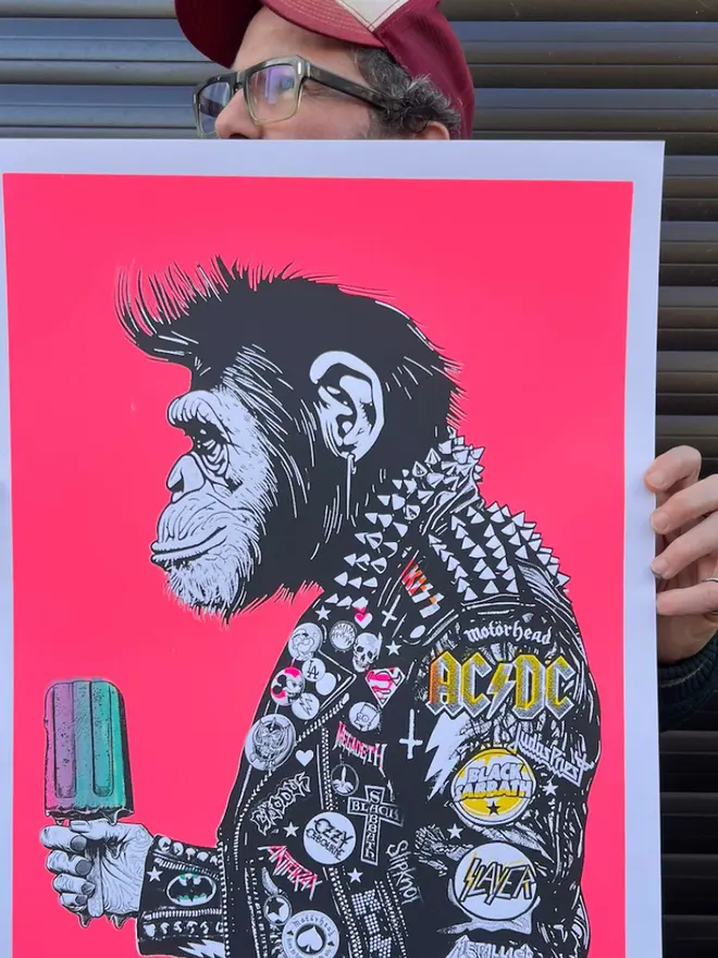 A side profile print of a metal monkey wearing a  punk leather jacket decorated with music band patches, holding an icecream against a neon pink background. 