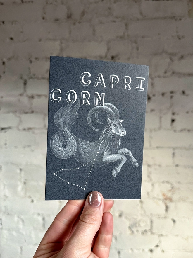 a greetings card featuring a greyscale illustration of a zodiac style sea goat with the text “CAPRICORN”
