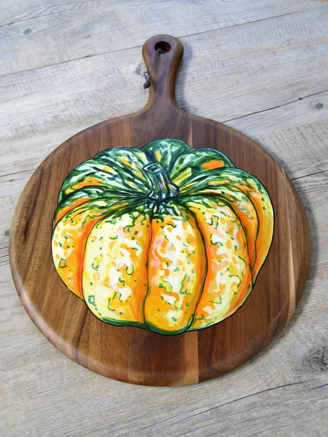 Wooden serving board with a handpainted design of a carnival squash