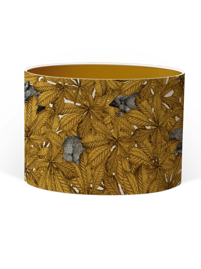 Handmade lampshade featuring cosy hedgehogs nestled among autumnal yellow leaves, creating a warm and whimsical woodland design.