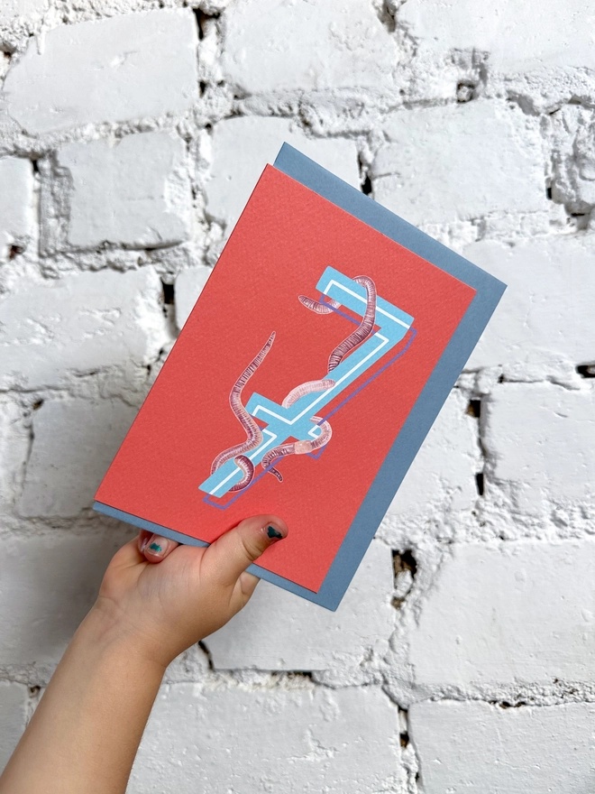 a bright red card with a big blue number 7 and some illustrated earthworms with a blue envelope