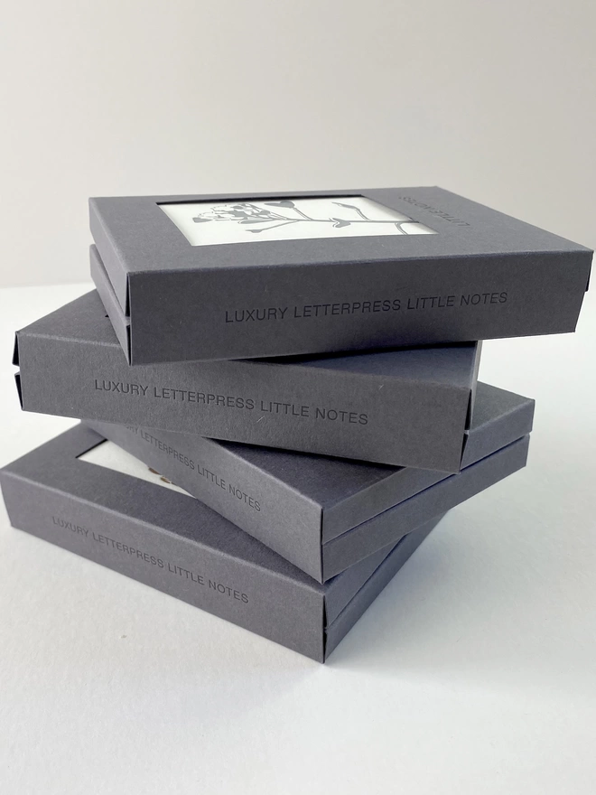 Side of letterpress gift boxes stacked with four different designs on the front of each one