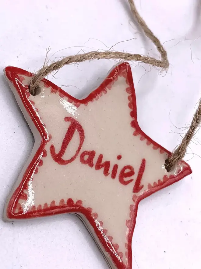 Personalised Ceramic Christmas Star Name Place Markers, a colourful star place marker sitting on a plain white surface. 