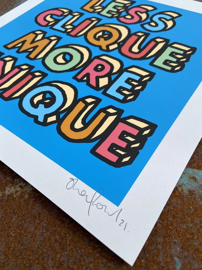  "Less Clique More Unique" Hand Pulled Screen Print blue background with multi colour letters with black hand drawn outline that spell out less clique more unique