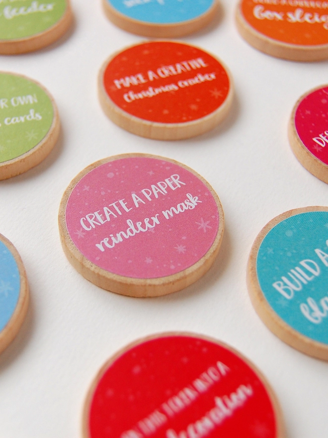 Several wooden tokens with brightly coloured labels lay on a white surface.