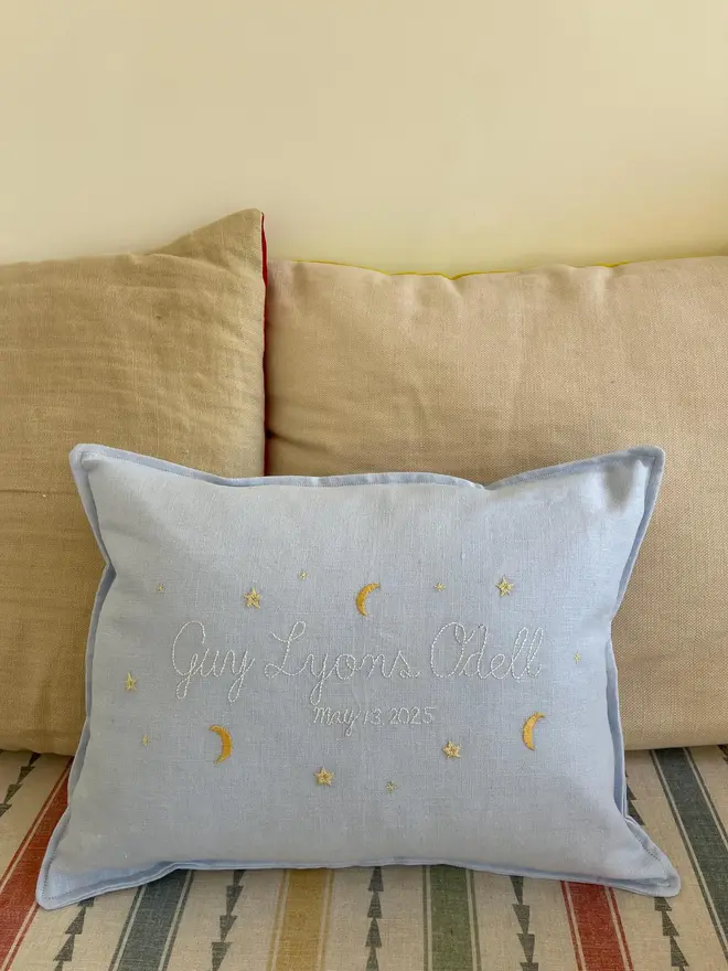 Personalised Handmade Embroidered Linen Cushion, pale blue cushion with name on sofa. 