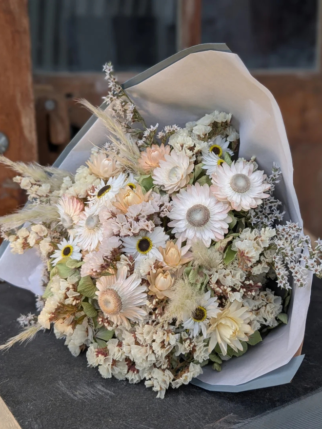 seashell dried flower bouquet. white and neutral coloured dried flower bouquet wrapped in paper.