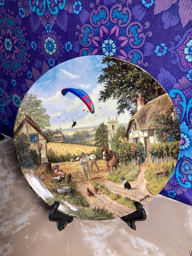 Vintage plate featuring a rural scene with a contemporary paraglider.