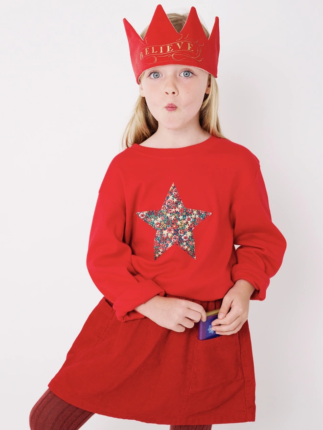 a 5 year old girl wearing a red Christmas t-shirt with a floral Liberty print star on the front