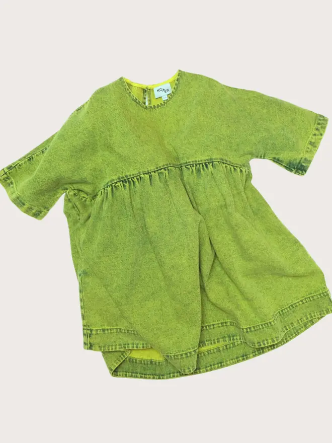 Front flat lay of the Studio Koter Rumi dress in green acid-wash denim, short-sleeved with a gathered empire waist.