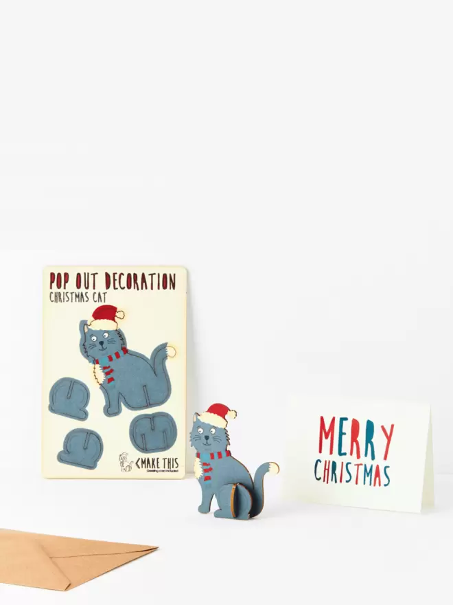 Black cat Christmas decoration and Merry Christmas card and brown kraft envelope on a white background