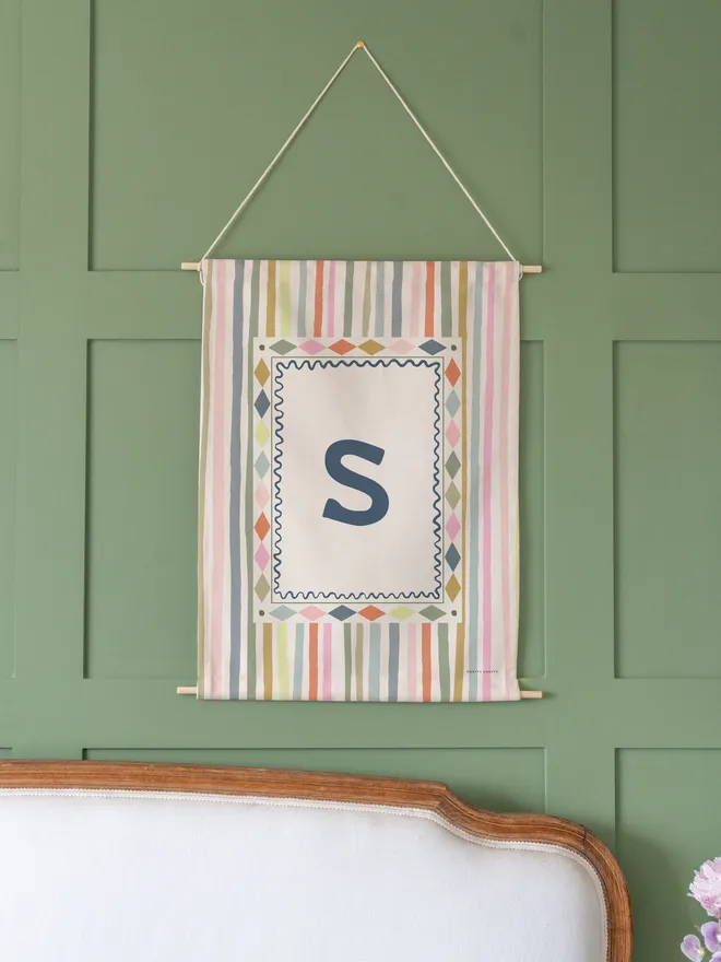 Stripe Initial Fabric Banner, hanging on a green wall. 