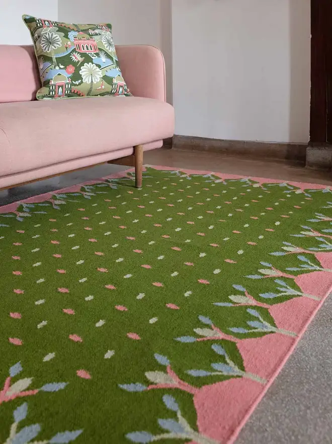 Hedgerow Flatweave Rug, a colourful rug sitting in a decorated room. It is accompanied by some household items.