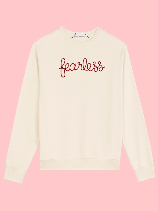 A natural sweatshirt embroidered with the phrase fearless on a pink background