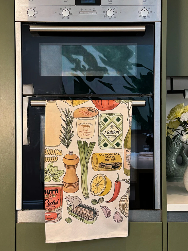 Cooking Essentials Tea Towel. A tea towel with illustrations of kitchen essentials like cheese, tomatoes, pasta.