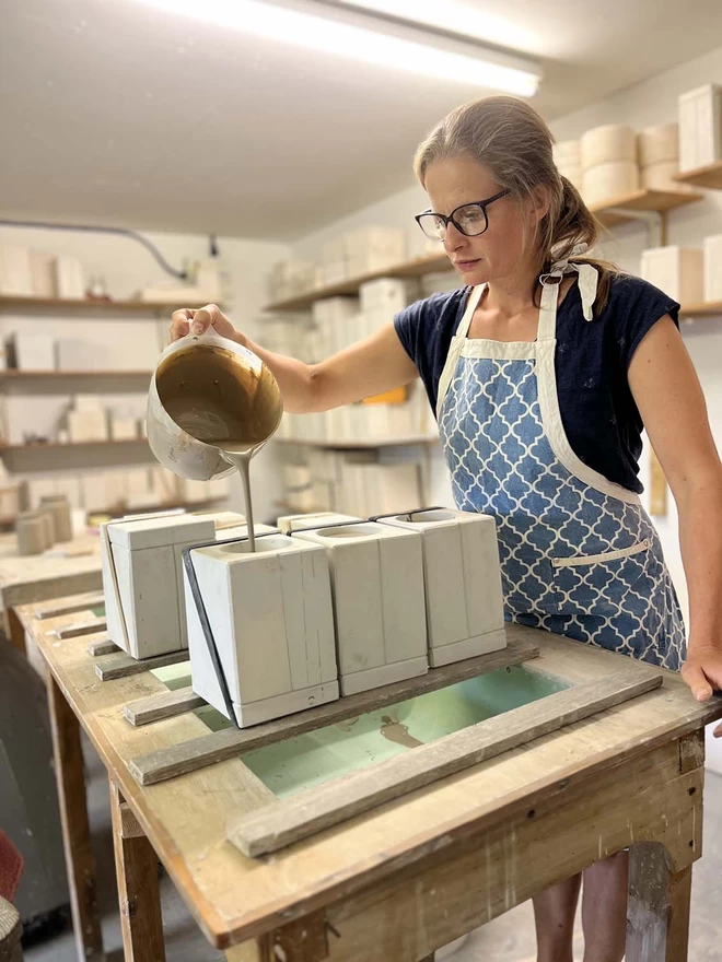 In her studio Katie is filling plaster ‘Brush Scrub Sparkle’ moulds with slip from a plastic jug.
