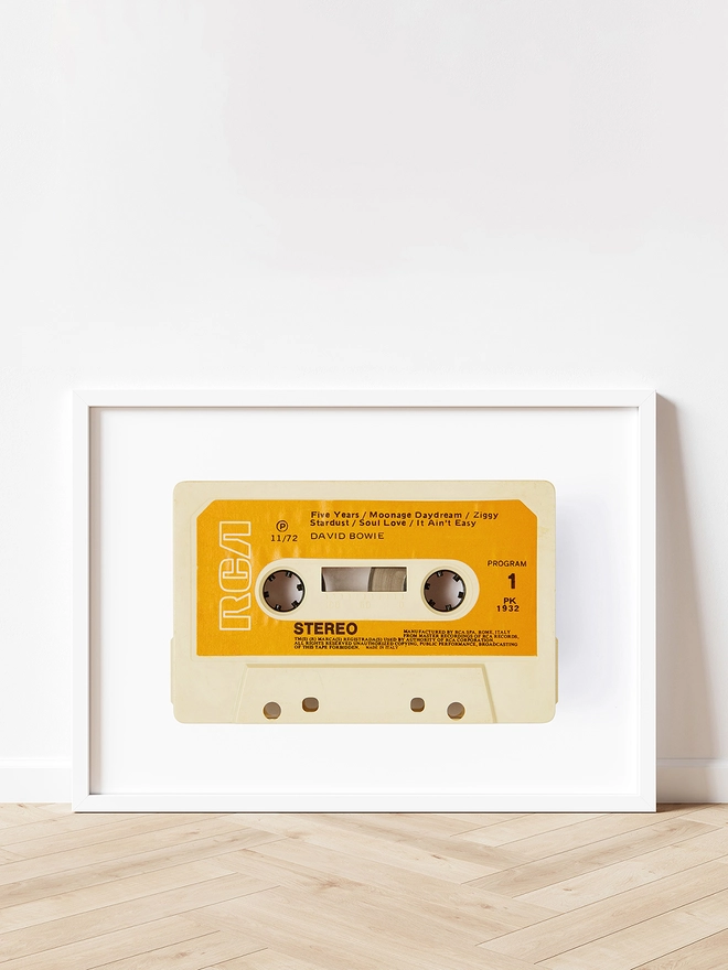 david bowie rise and fall of ziggy stardust cassette print. framed print propped up against white wall and wooden floor.
